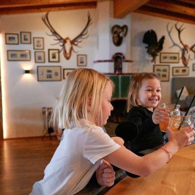 Zwei Kinder stoßen mit Getränken an einer rustikalen Bar an